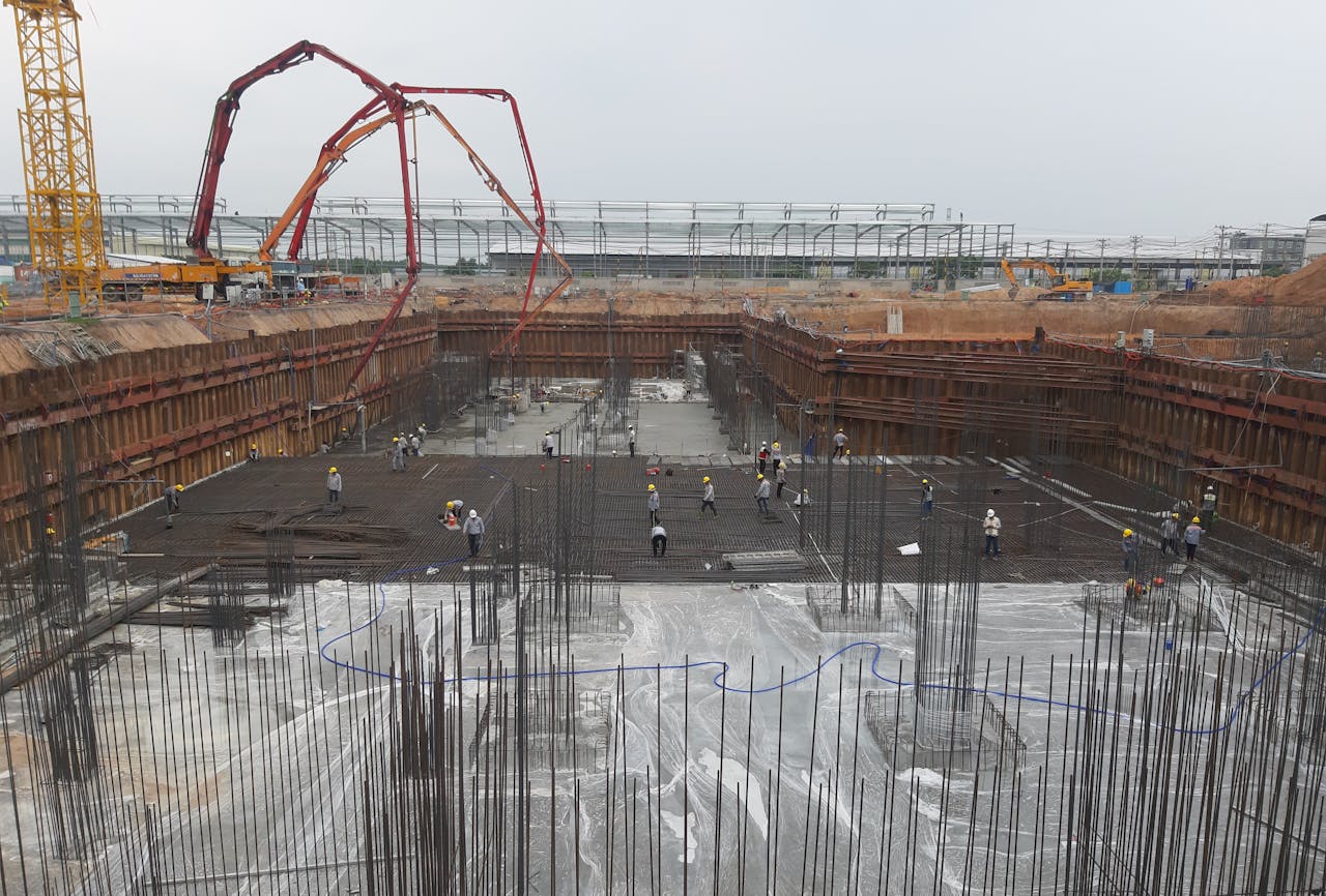 Construction site with workers setting foundation and steel reinforcements.